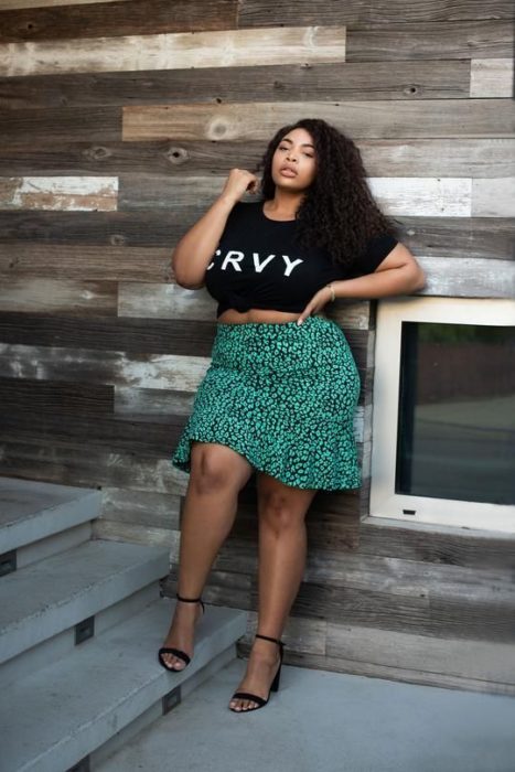 Mujer curvy morena con blusa negra y falsa sirena verde