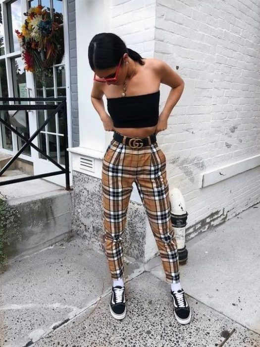 Chica se acomoda su pantalón y usa crop top negro con pantalón amarillo a cuadros