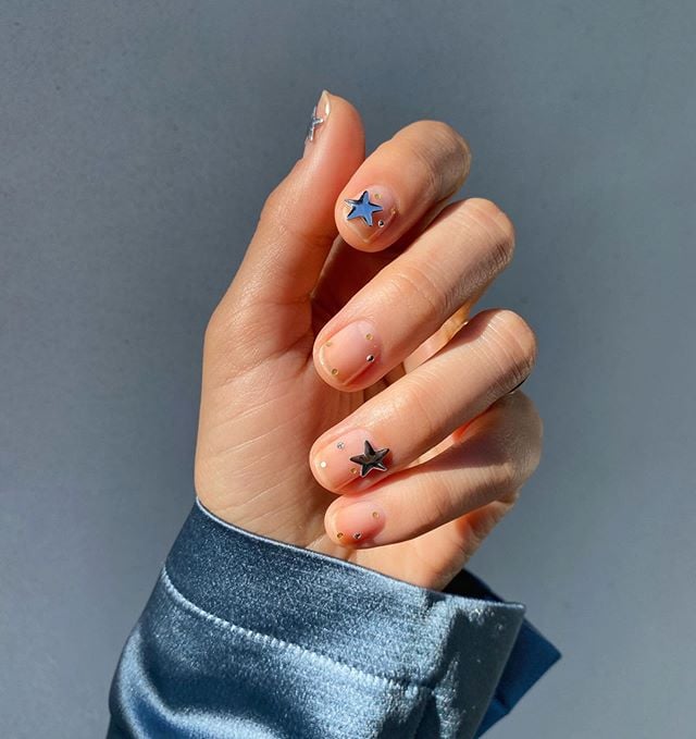 Diseños de uñas de Betina Goldstein con estrellas grandes en el dedo medio e indice 