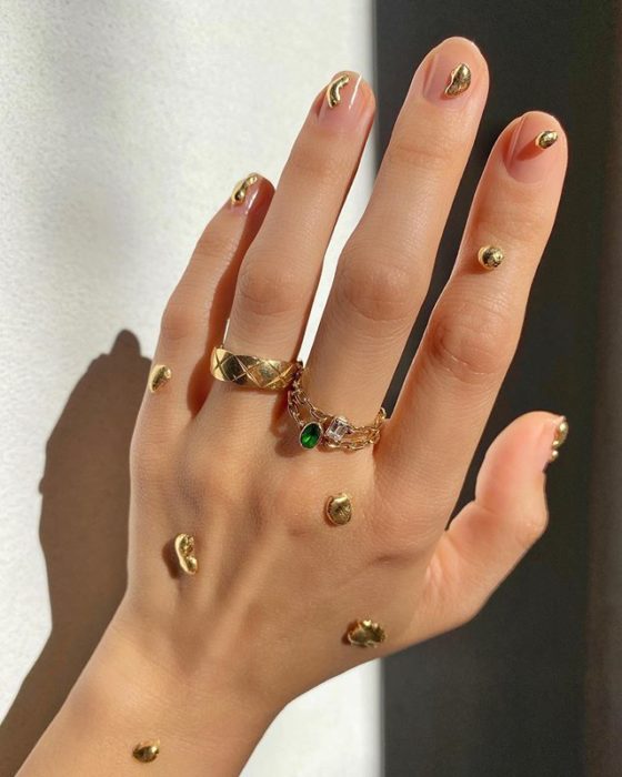 Diseños de uñas de Betina Goldstein con gotas doradas en las uñas 