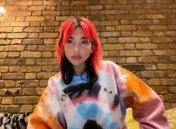 Dua Lipa con el cabello teñido en colores rosas con rojo en la parte inferior 