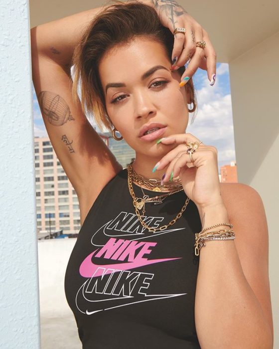 Rita Ora posando para una fotografía mientras usa un top nike y varias joyas 