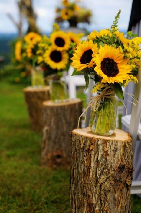 Decoración de boda con troncos y frascos con girasoles