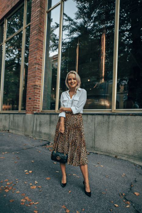 Chica usando una falda midi con estampado animal print con una blusa de seda de color blanco 