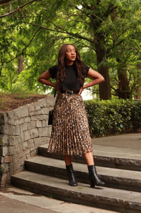 Chica usando una falda midi con estampado animal print con una blusa de color negro 