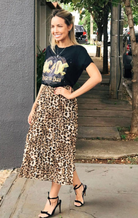 Chica usando una falda midi con estampado animal print con una blusa de color negro con el logo de AC/DC