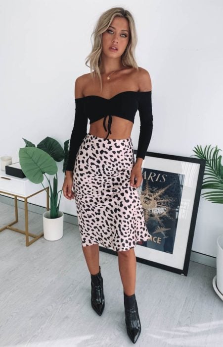 Chica usando una falda midi con estampado animal print con un crop top de color negro