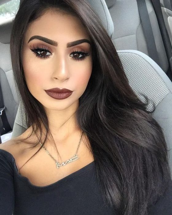 Chica latina de cabello largo y negro suelto usa labial marrón 