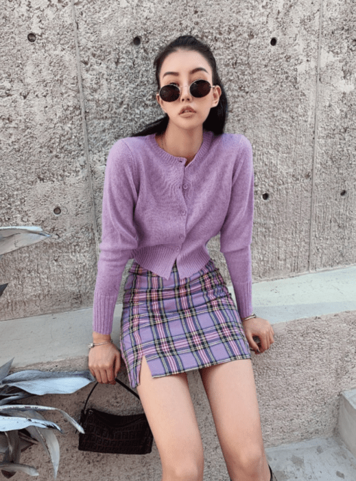 Chica usando falda con estampado tartán y suéter delgado color lavanda