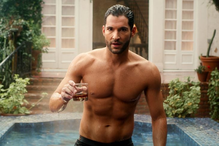 Tom Ellis, actor, protagonista serie Lucifer, saliendo de la piscina sin camisa y sosteniendo un vaso de vidrio con whisky