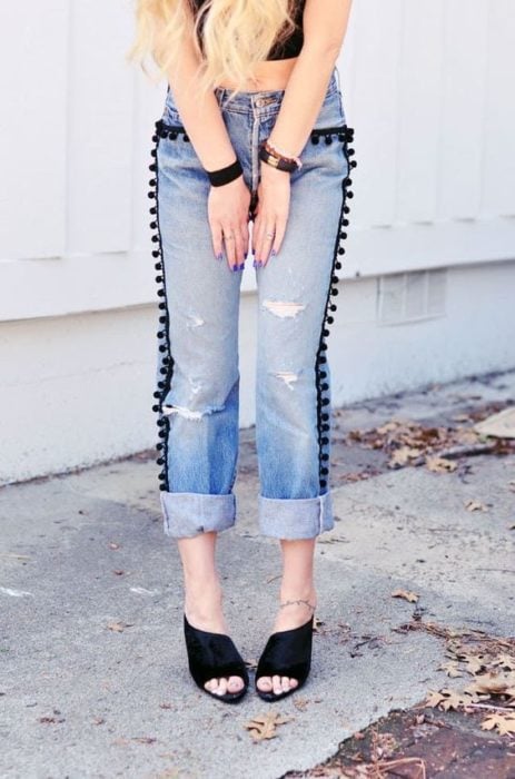 Jeans deslavados con pompones negros a los costados