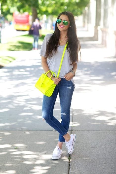 Chica con jeans, blusa blanca y bolso verde neón
