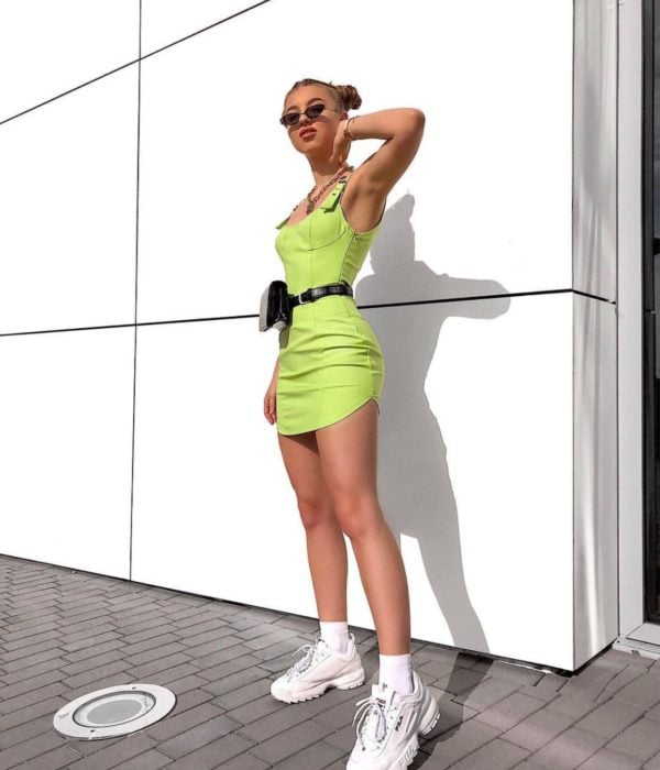 Chica rubia con vestido verde neón y tenis blancos