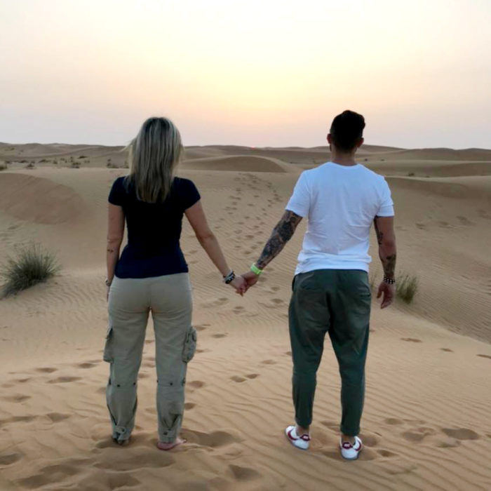 Pareja de novios tomada de la mano mirando al horizonte en el desierto