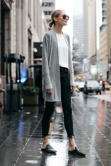 Chica con pantalón negro y blusa blanca con cardigan gris