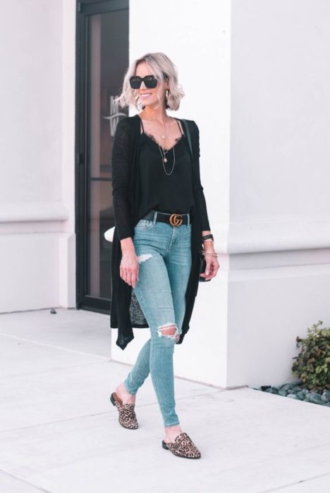 Chica rubia con jeans rotos y blusa y cardigan negros