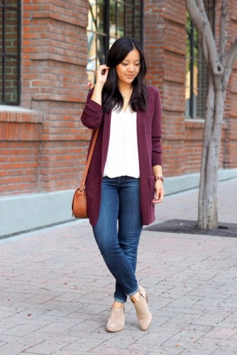 Chica morena con jeans, blusa blanca y cardigan color vino