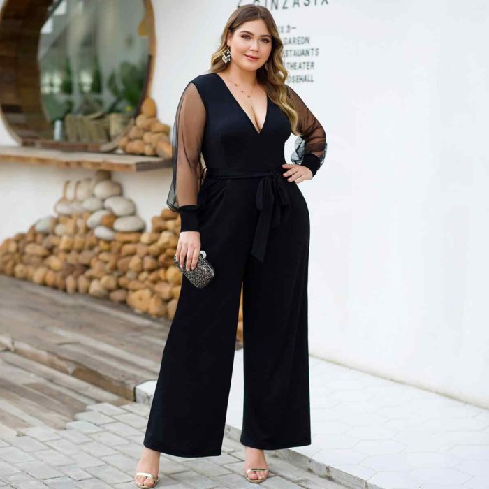 Chica curvy usando un jumpsuit de color negro con mangas transparentes y un bolso pequeño 