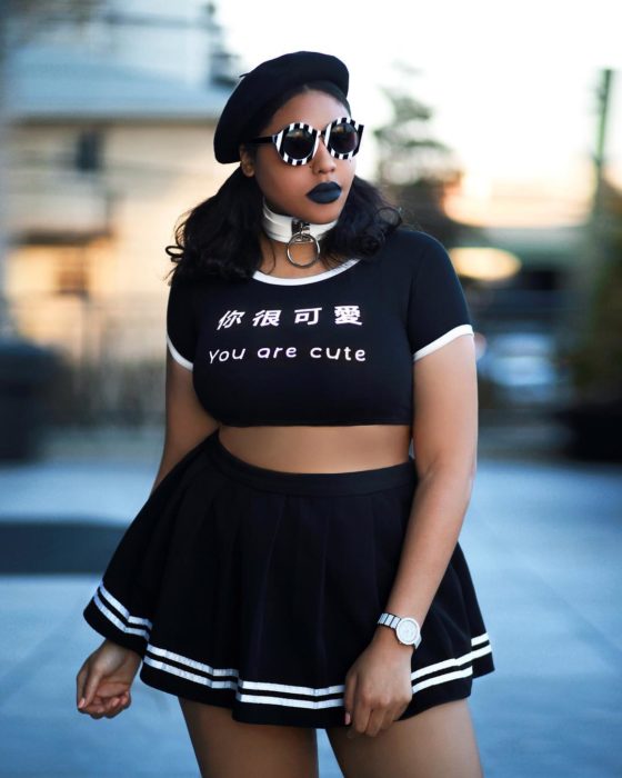 Chica curvy usando una falda plizada y un crop top con letras blancas