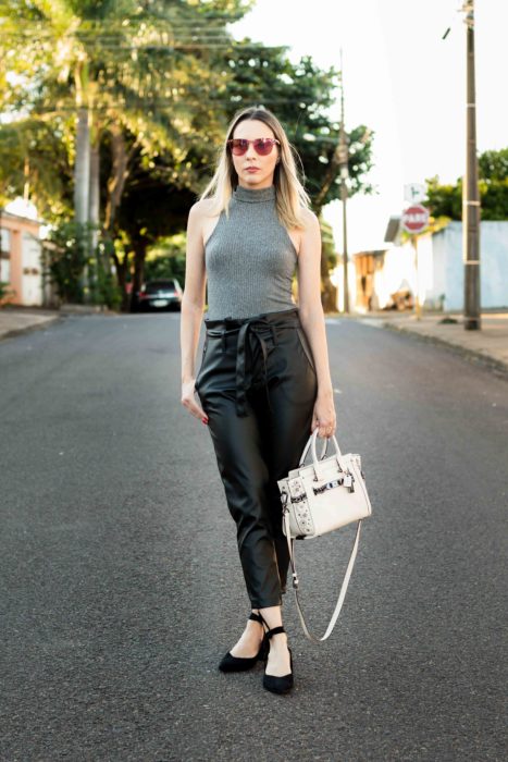 Mujer rubia posando en medio de la calle con blusa alter gris y paper bag pants negros tipo cuero