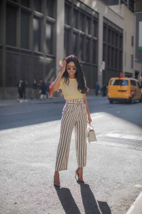 Mujer morena de cabello largo y negro con blusa amarillo con paper bag pants rayados