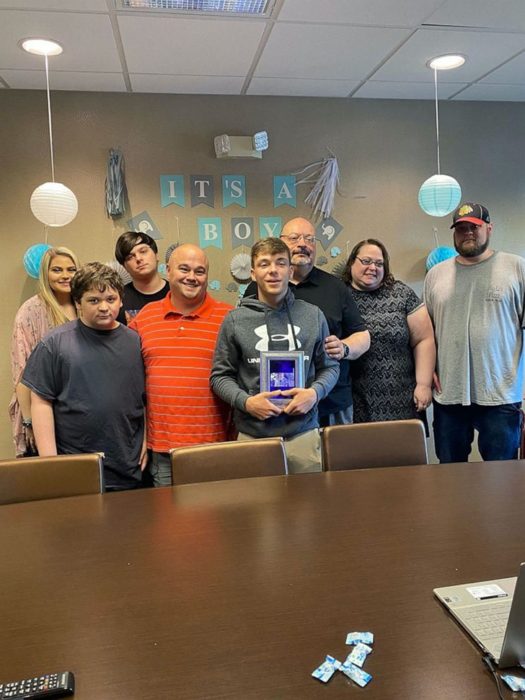 Familia reunida frente a un computador sonriendo por la sesión de adopción de un chico de 17 años