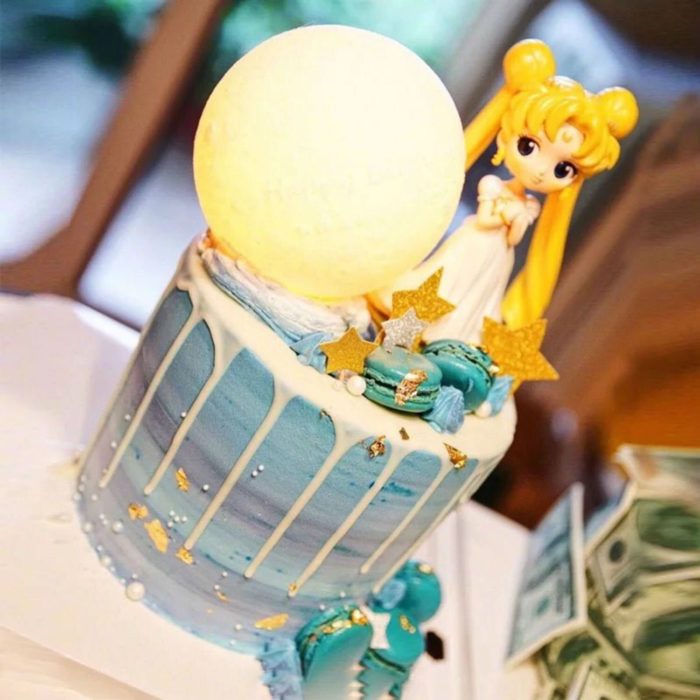 Pastel de Sailor Moon con Serena y una luna enorme, en tonalidadez azules y chorreado de chocolate blando 