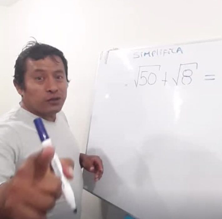 Fidel Medina explicando matemáticas en una pizarra blanca, usando plumones azules