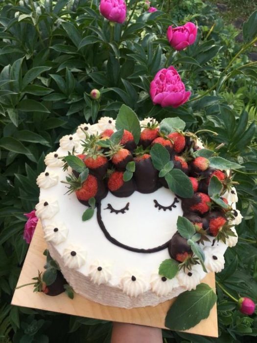 Pastel de vainilla decorado con fresas con chocolate como si fueran una cabellera larga