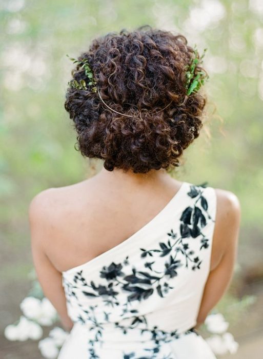 Recogido para novia de cabello rizado con tocado de plantas