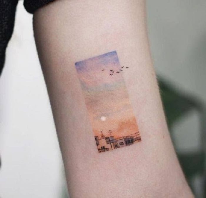 tatuaje de atardecer con tonos de colores arcoíris