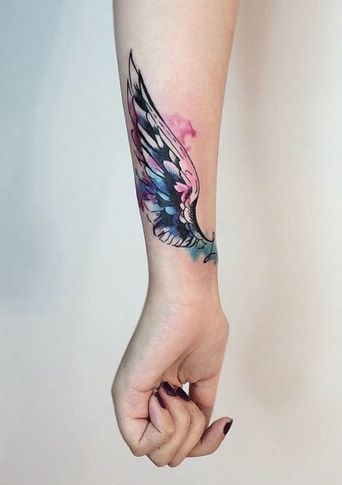 Tatuaje de ala colorida en brazo de mujer
