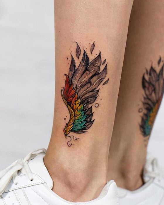 Tatuaje de alas coloridas en tobillo de mujer
