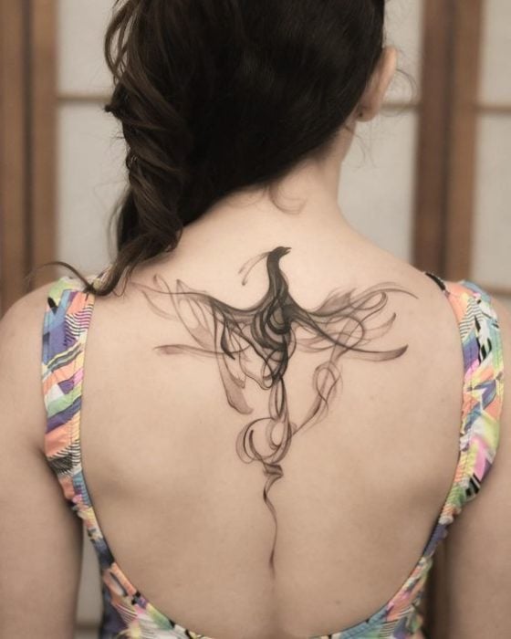 Tatuaje de ave fénix en espalda de mujer