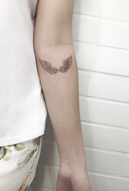 Tatuaje de alas en blanco y negro en brazo de mujer