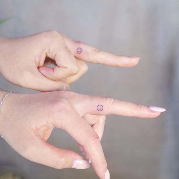 Tatuajes para compartir con tu mejor amiga con diseño d euna carita feliz en el dedo medio de la mano derecha