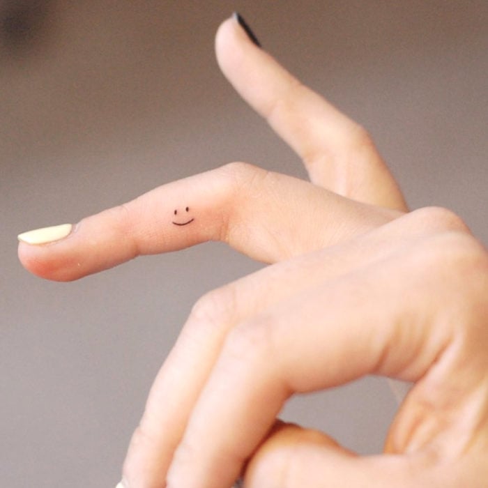 Tatuajes pequeños; minitatuaje de carita feliz en el dedo
