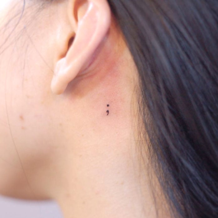 Tatuajes pequeños; minitatuaje de punto y coma detrás de la oreja
