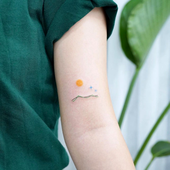 Tatuajes pequeños; minitatuaje de paisaje en el brazo, sol y estrellas