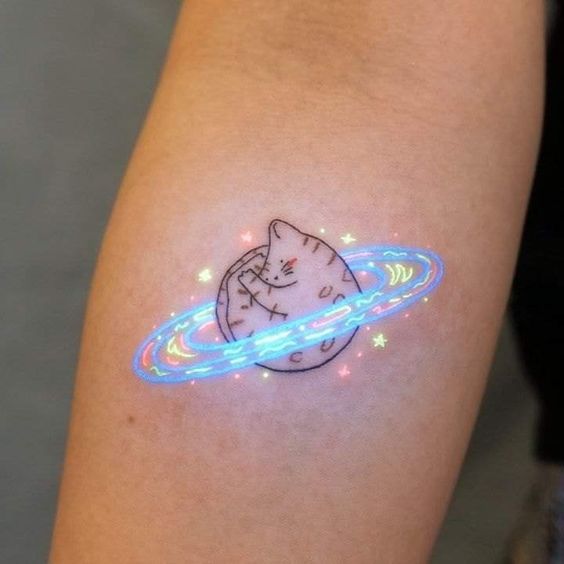 Mini tatuaje de gatito hecho bola en una galaxia
