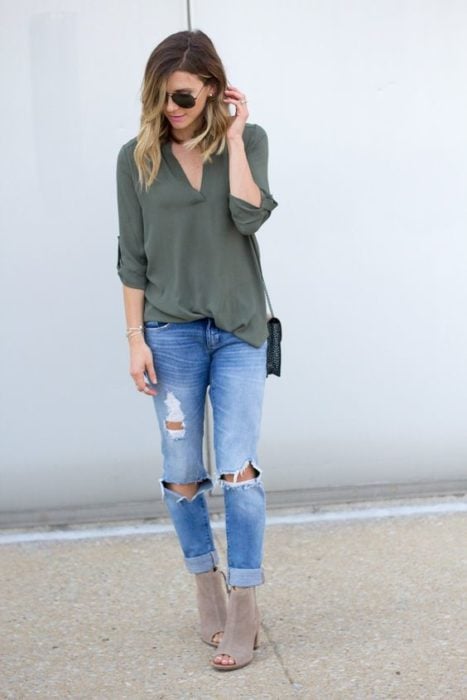 Chica rubia con blusa verde militar y jeans rotos con botines grises