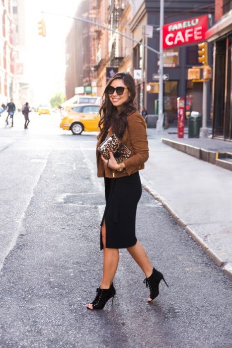 Mujer cruza la calle con gafas de sol negras, saco café, falda de lápiz negra y botines de tacón de aguja negros