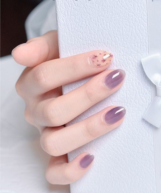 manos de mujer con manicura en tonos violeta con efecto de transparencia