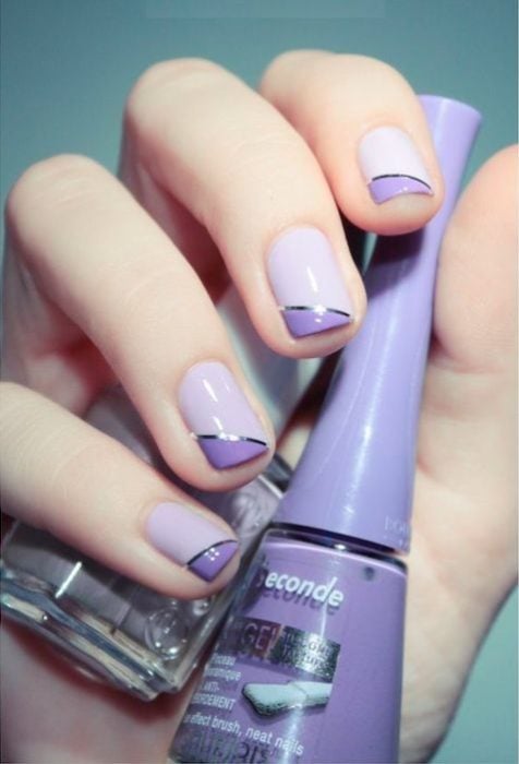 manos de mujer con manicura en tonos violeta y morado con detalle de cintillas en plata