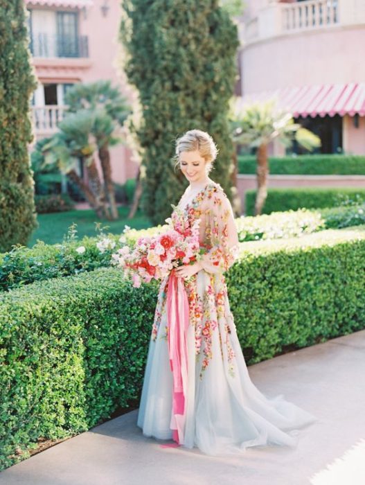 Novia con vestido azul lleno de flores sosteniendo un ramo