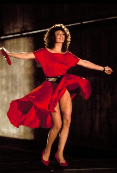 Kelly LeBrock en La mujer de rojo caminado sobre la calle mientras su vestido de color rojo vuela 