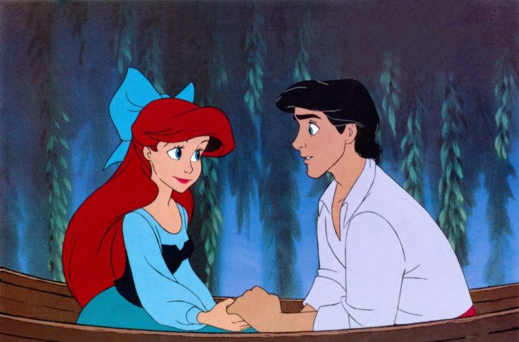 Escena d ela película La Sirenita de Disney, Ariel y Eric tomados de las manos sobre una lancha de madera