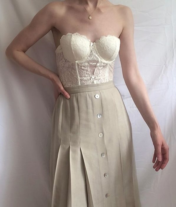 chica usando bustier blanco de encaje con una falda midi beige con botones