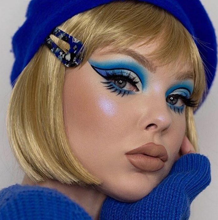 chica rubia con maquillaje monocromático en colores azules, sombra de ojos azul y blanca, delineado sesentero tipo cat-eye y labial nude matte mate