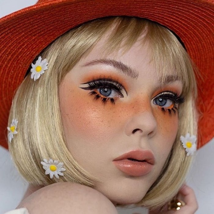 chica rubia usando un sombrero naranja con maquillaje en colores anaranjados